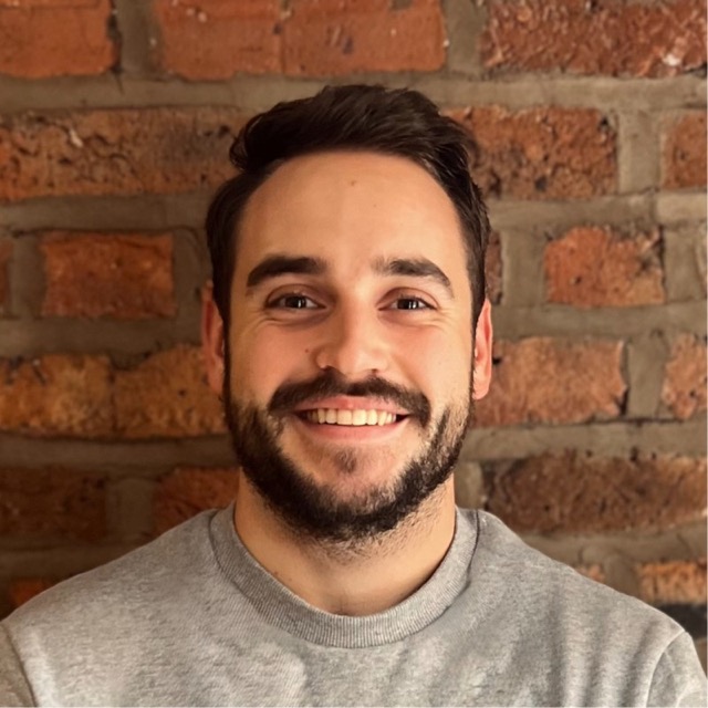 Damian Pickett, smiling in front of a brick wall